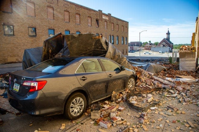 A car is covered in bricks and roofing material in Marshalltown, Iowa, on Tuesday Aug. 11, 2020.