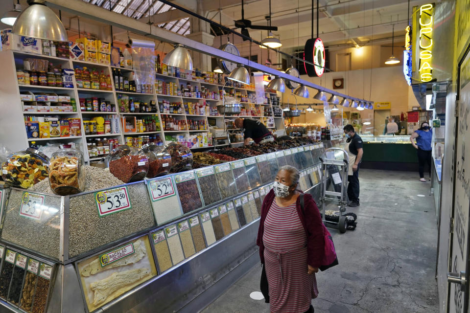 A woman walks past a shop at the Grand Central Market, Monday, Nov. 16, 2020, in Los Angeles. Gov. Gavin Newsom announced Monday, Nov. 16, 2020, that due to the rise of COVID-19 cases, some counties have been moved to the state's most restrictive set of rules. The new rules begin Tuesday, Nov. 17. (AP Photo/Marcio Jose Sanchez)