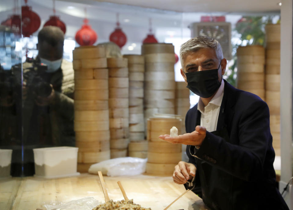 FILE - In this file photo dated Monday, May 17, 2021, Mayor of London Sadiq Khan, holds a dumpling he prepared, during a visit to Dumplings Legend in China Town central London. Khan on Thursday July 22, 2021, sent a message of support to Hong Kong people fleeing China’s crackdown on democracy to seek a new life in the U.K., saying his office will spend 900,000 pounds (dollars 1.2 million US) to help new arrivals with housing, education and finding jobs. (AP Photo/Alastair Grant, FILE)