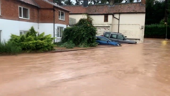 Pub and houses semi-submerged as deep floodwater rushes down road in Nottinghamshire village (PA)
