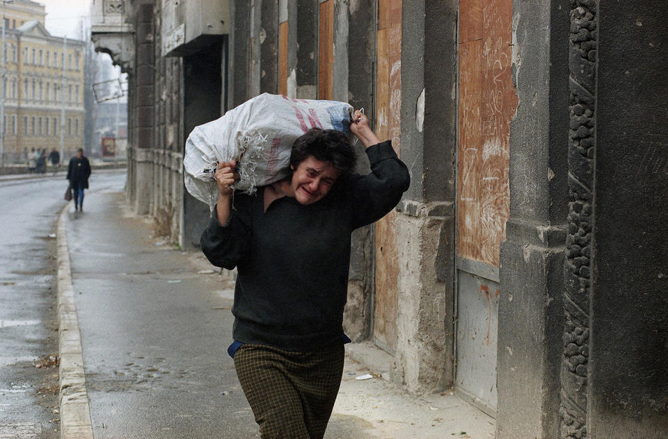 <p>A woman in Sarajevo cries while she struggles to carry a sack of firewood to her home as winter weather makes life more difficult for the city’s residents, Nov. 27, 1994. (Photo: Jacqueline Larma/AP) </p>