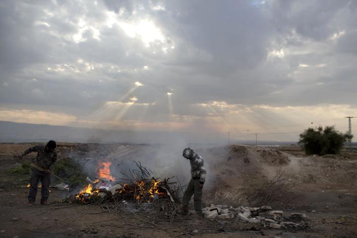 Palestinian farmers burn agriculture waste just outside the West Bank Jordan Valley Jewish settlement of Petsael, Thursday, Jan. 9, 2014. For Israeli farmers in the West Bank's Jordan Valley, an international campaign to boycott settlement products has turned almost overnight from a distant nuisance into a harsh economic reality. The export-driven income of growers in the valley's 21 settlements dropped by 15 percent, or $29 million dollars, last year because Western European supermarket chains trying to avoid political entanglements largely stopped buying the valley's grapes, dates and sweet peppers. (AP Photo/Oded Balilty)