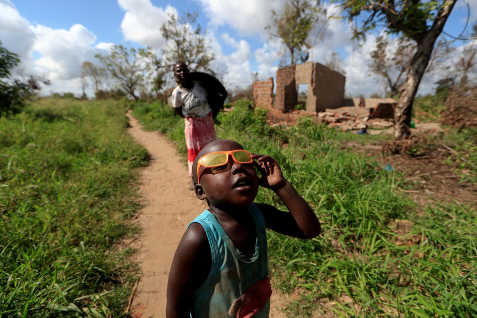 Ester Thoma walks past her damaged house as a boy plays with his glasses in the aftermath of Cyclone Idai, in the village of Cheia, which means "Flood" in Portuguese, near Beira, Mozambique April 1, 2019. (Photo: Zohra Bensemra/Reuters)  