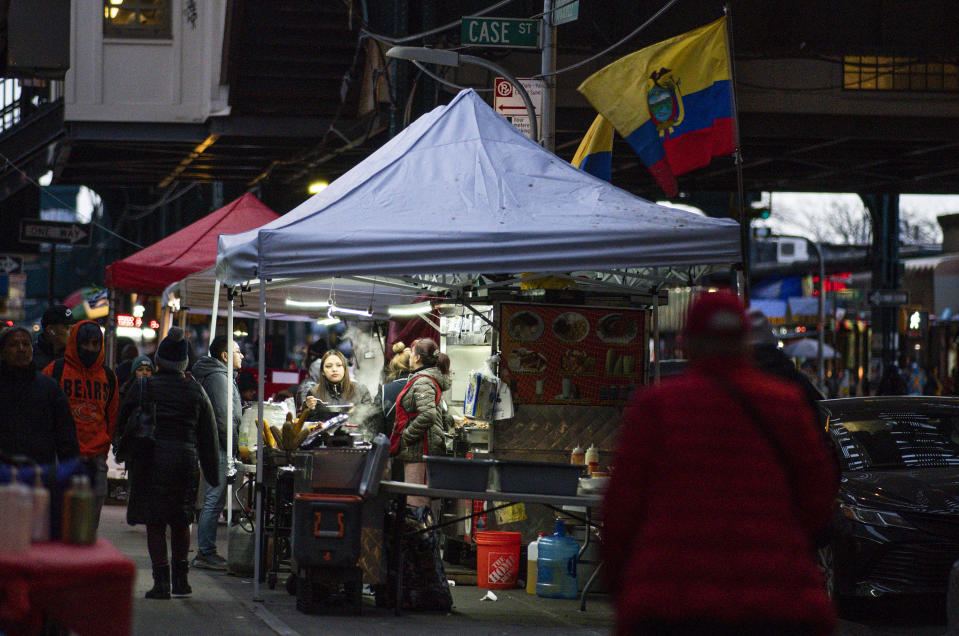 Pedestrians pass food tents attended by a Ecuadorian vendors, Monday, Feb. 27, 2023, in the Queens borough of New York. Ecuador — long known for remarkably low rates of crime, despite sitting in South America's cocaine heartland — has been struggling economically, fighting higher violence and losing its people in record numbers. Many are headed to the U.S. (AP Photo/Eduardo Munoz Alvarez)