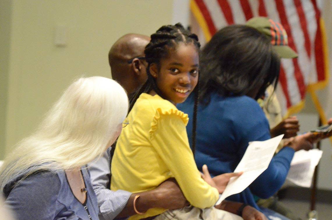 Ayahn Ambroise, 12, (center in yellow) is congratulated after she lead the pledge of allegiance and read an essay to the CMS board on Tuesday, April 4, 2023. The sixth-grader Ambroise at Eastway Middle School, has advocated for affordable housing, even leading a march through a local neighborhood to raise funds.