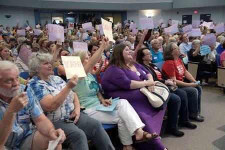 Attendees hold up signs in response to answers from U.S. Representative Ted Yoho (R-FL) during a town hall meeting in Gainesville, Florida, U.S., April 10, 2017. REUTERS/Phelan Ebenhack