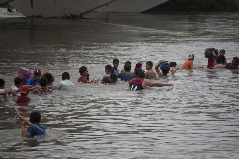 A group of Central American migrants wade across the Suchiate River, on the the border between Guatemala and Mexico, in Ciudad Hidalgo, Mexico, Saturday, Oct. 20, 2018. After Mexican authorities slowed access through the border bridge to a crawl, hundreds of migrants began boarding rafts or wading across the river and crossing into Mexico illegally. (AP Photo/Moises Castillo)