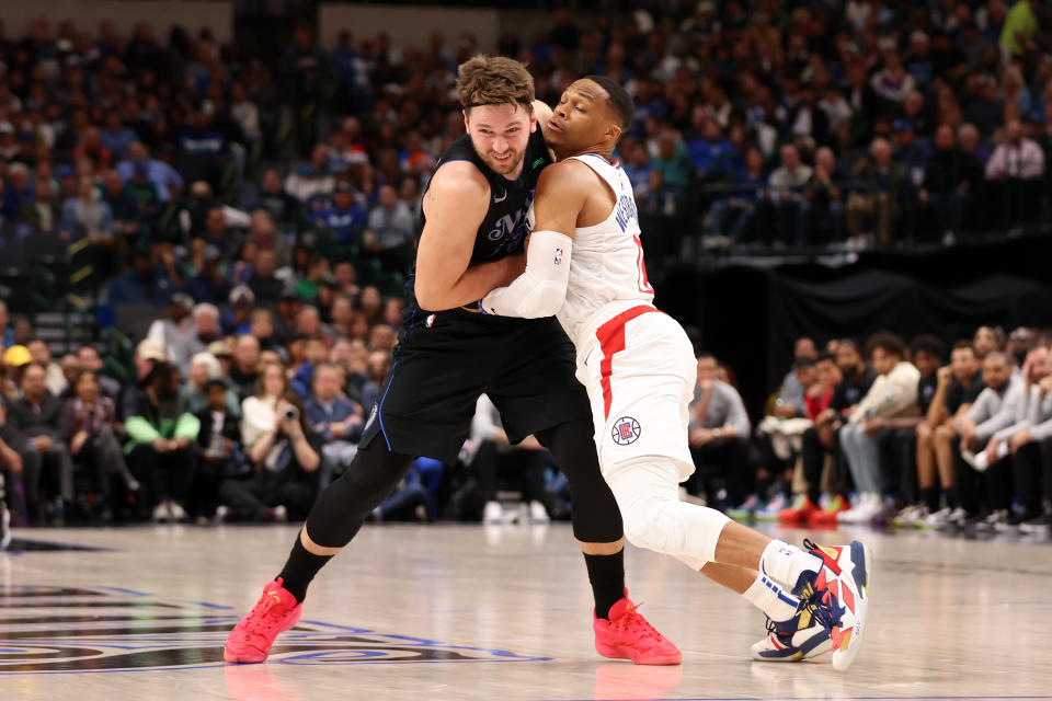 DALLAS, TEXAS - DECEMBER 20: Luka Doncic #77 of the Dallas Mavericks and Russell Westbrook #0 of the LA Clippers fight for position in the first half  at American Airlines Center on December 20, 2023 in Dallas, Texas. NOTE TO USER: User expressly acknowledges and agrees that, by downloading and or using this photograph, User is consenting to the terms and conditions of the Getty Images License Agreement. (Photo by Tim Heitman/Getty Images)