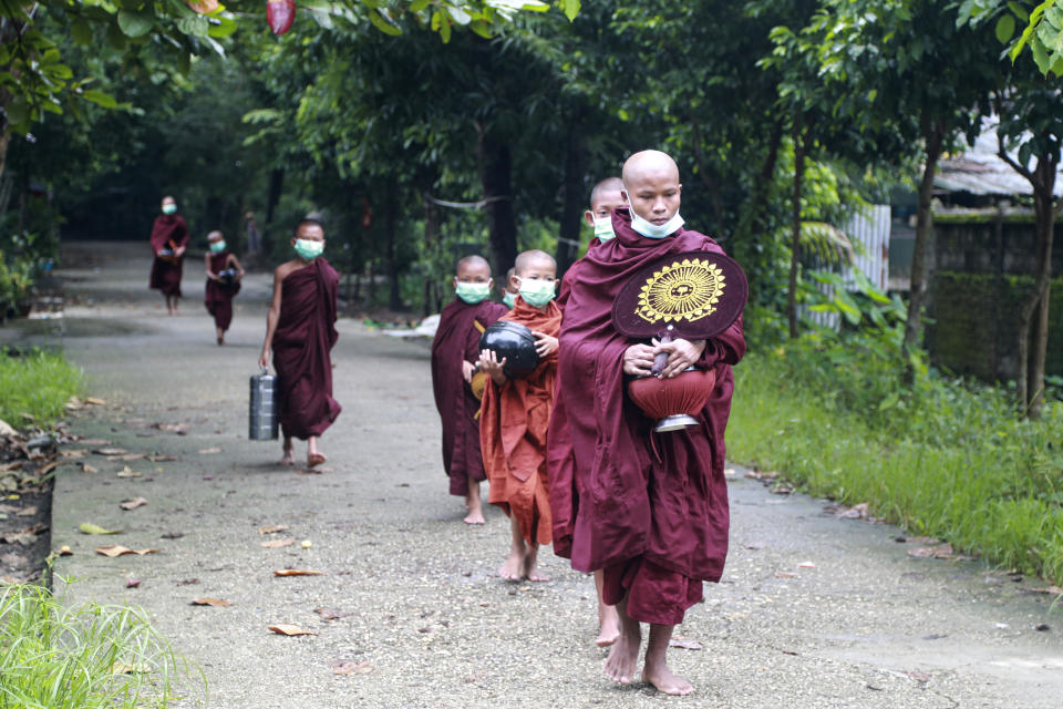 Buddhist monks wearing face mask walk as they collect morning alms Thursday, July 15, 2021, in Yangon, Myanmar. (AP Photo/Thein Zaw)