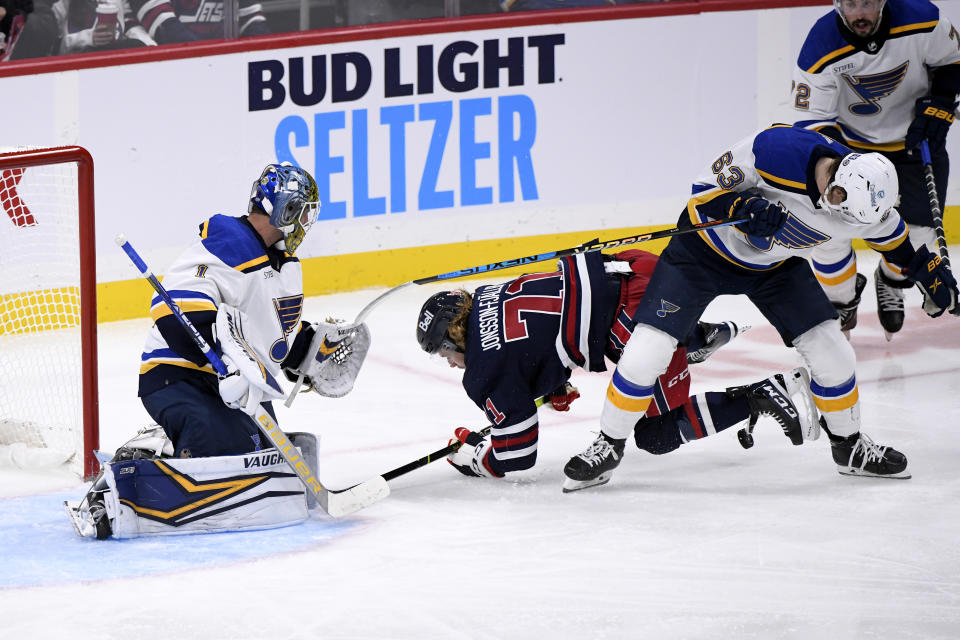 Winnipeg Jets' Axel Jonsson-Fjallby (71) and St. Louis Blues' Jake Neighbours (63) battle for the puck in front of Blues goaltender Thomas Greiss (1) during the third period of NHL hockey game action in Winnipeg, Manitoba, Monday, Oct. 24, 2022. (Fred Greenslade/The Canadian Press via AP)