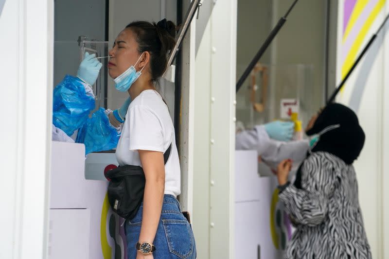 Healthcare workers take nasal swab samples from local residents for a COVID-19 test in Bangkok