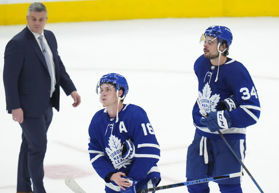 Toronto Maple Leafs forward Mitchell Marner (16) and teammate Auston Matthews (34) look on next to their head coach Sheldon Keefe after being knocked out of the Stanley Cup playoffs in Game 7 of an NHL hockey first-round playoff series against the Tampa Bay Lightning in Toronto, Saturday, May 14, 2022. (Nathan Denette/The Canadian Press via AP)