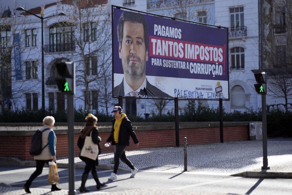 FILE - People walk by a billboard for Andre Ventura, leader of populist radical right party Chega (in English, Enough) with the words, "We pay so many taxes to sustain corruption", in Lisbon, March 4, 2024. Corruption scandals have cast a shadow over Portugal's March 10 snap election. They have also fed public disenchantment with the country's political class. (AP Photo/Armando Franca, File)