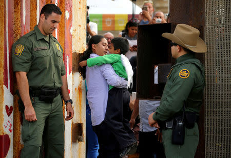 FILE PHOTO - U.S. Border patrol agents stand at an open gate on the fence along the Mexico border to allow Luis Eduardo Hernandez-Bautista hug Ty'Jahnae Williams and his father Eduardo Hernandez (not in view), as part of Universal Children's Day at the Border Field State Park, California, U.S. on November 19, 2016. REUTERS/Mike Blake/File Photo