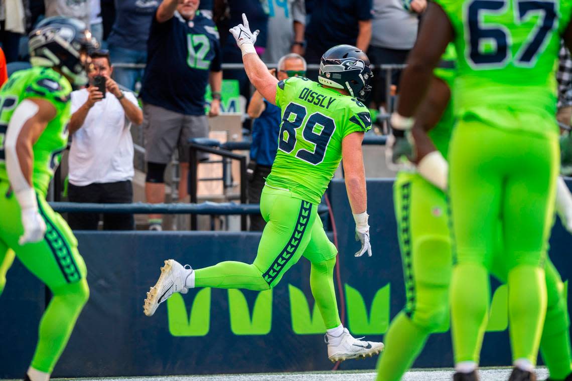 Seattle Seahawks tight end Will Dissly (89) holds his hand up and runs by fans after scoring the first touchdown of the game in the first quarter of an NFL game on Monday, Sept. 12, 2022, at Lumen Field in Seattle.