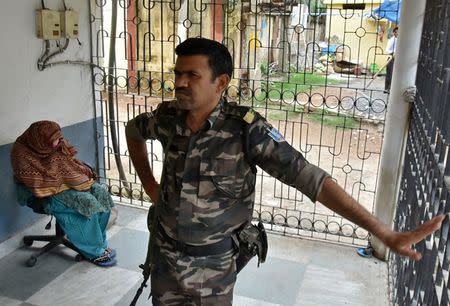 A policeman stands next to a woman (face covered) after authorities charged her with baby trafficking at a court in Ranchi, July 5, 2018. REUTERS/Stringer