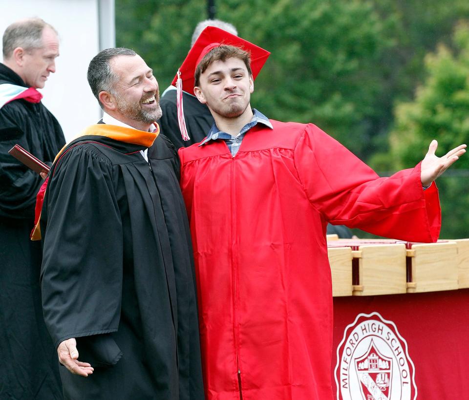 Graduate Samuel Daniel Deans strikes a pose — and gets a laugh out of School Committee Chair Christopher Wilson — as he receives his diploma at Milford High School's graduation ceremony, June 4, 2023.