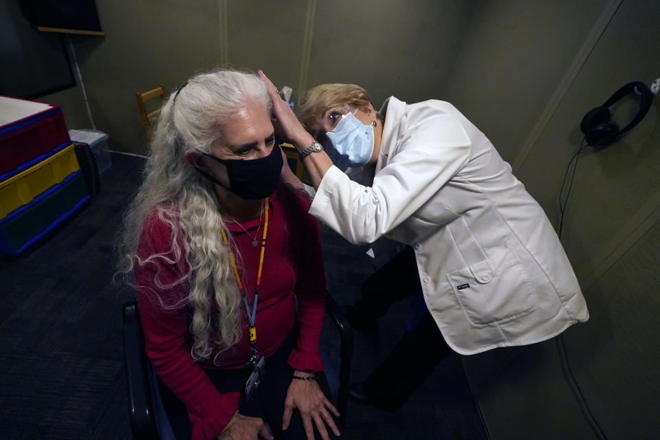 Andrea Gohmert, right, director of the hearing clinic at the University of Texas at Dallas’ Callier Center for Communication Disorders, prepares Lynne Perler for a hearing test during a demonstration at the Callier Center for Communication Disorders Friday, Oct. 23, 2020, in Dallas. Hearing specialists across the U.S. are seeing an uptick in visits from people who only realized how much they relied on lip reading and facial expressions when people started wearing masks because of the coronavirus pandemic. (AP Photo/LM Otero)