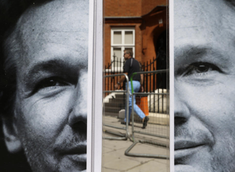 FILE - In this Tuesday, Aug. 14, 2012 file photo, a pedestrian walks past a photograph of WikiLeaks founder Julian Assange, placed by supporters across the street from the Ecuadorian Embassy in central London. Police in London arrested WikiLeaks founder Assange at the Ecuadorean embassy Thursday, April 11, 2019 for failing to surrender to the court in 2012, shortly after the South American nation revoked his asylum. (AP Photo/Lefteris Pitarakis, File)