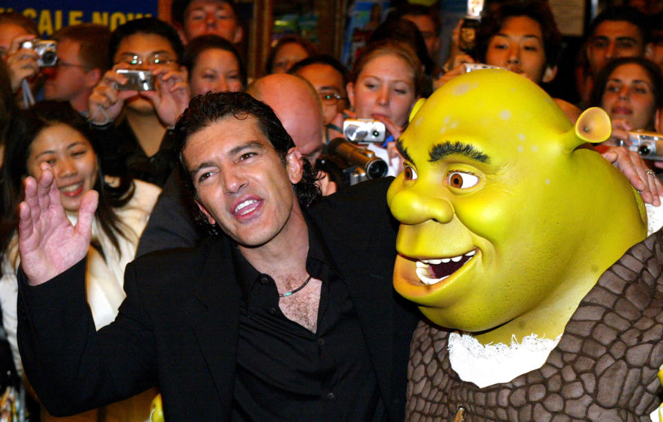 Antonio Banderas (L) interacts with a man in a Shrek suit before the Australian premiere of Shrek 2 outside a theatre in Sydney June 9, 2004. Banderas joins other high-profile Hollywood stars in the animation block buster and is the voice for the 'great ogre slayer' Puss-in-Boots. REUTERS/Will Burgess WB/LA