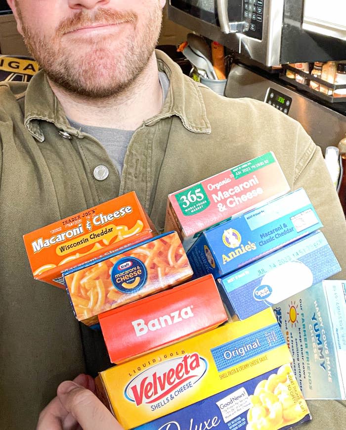 Author holding up a variety of boxes of mac 'n' cheese while taking a selfie