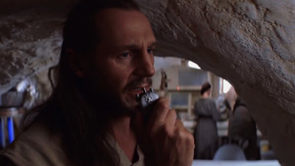 Qui Gon speaking into his communicator.