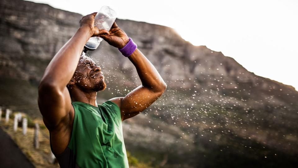 athlete splashing himself with water from his water bottle after a hard morning run