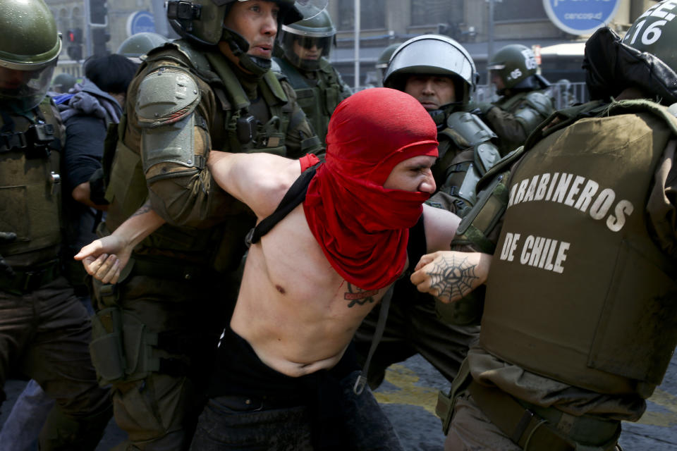 In this Oct. 14, 2018 photo, a protester is detained by police during a march against the commemoration of the discovery of the Americas, organized by indigenous groups demanding autonomy and the recovery of ancestral land, in Santiago, Chile. Protesters also demonstrated against Chile's anti-terrorism law, under which many Mapuche Indians are under arrest. (AP Photo/Esteban Felix)