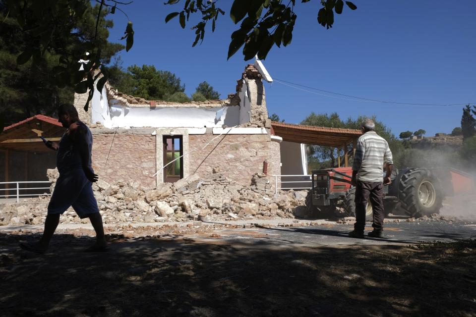 Residents pass next to a damaged Greek Orthodox chapel after a strong earthquake in Arcalochori village on the southern island of Crete, Greece, Monday, Sept. 27, 2021. A strong earthquake with a preliminary magnitude of 5.8 has struck the southern Greek island of Crete, and Greek authorities say one person has been killed and several more have been injured. (AP Photo/Harry Nikos)