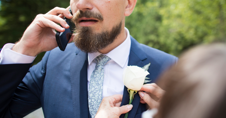 A groom looks stressed as he talks on the phone.