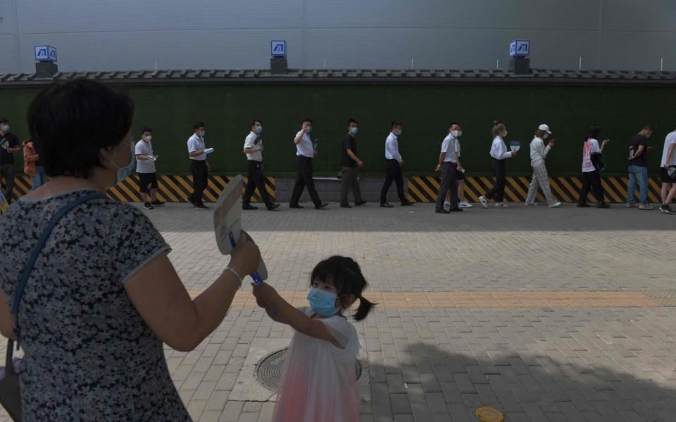 People wait in line to undergo COVID-19 coronavirus swab tests at a testing station in Beijing - GREG BAKER/AFP