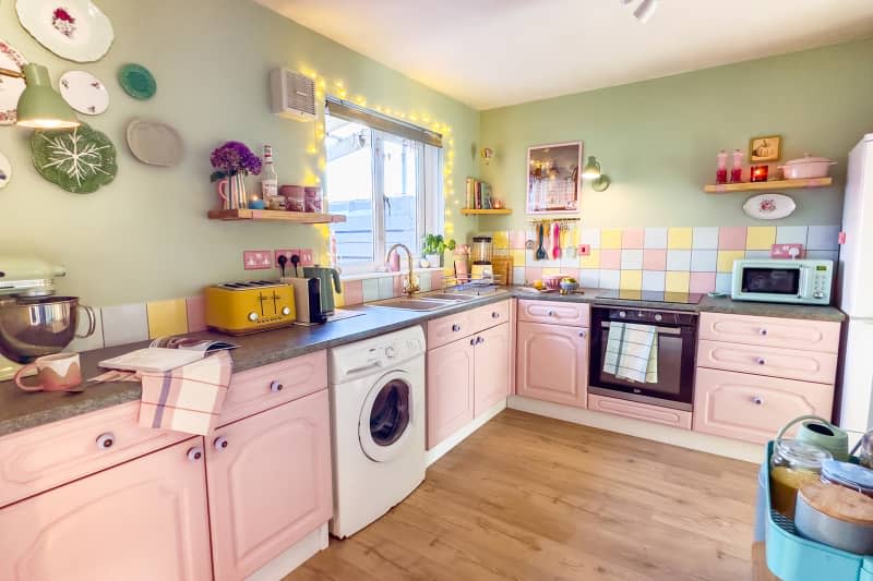 Pastel kitchen with green walls, pastel tiling, pink cabinetry, and pastel appliances and accessories