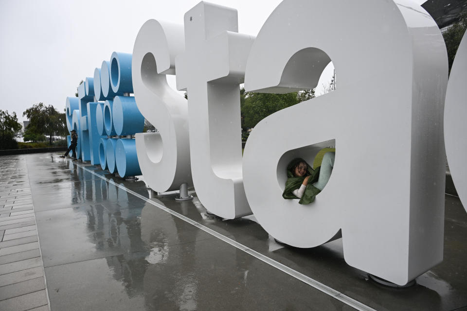 Davis Calvert, 11, of Pasadena, sits in the logo of SoFi Stadium in the rain before an NFL football game between the Los Angeles Chargers and the New Orleans Saints in Inglewood, Calif., Sunday, Aug. 20, 2023. (AP Photo/Alex Gallardo)