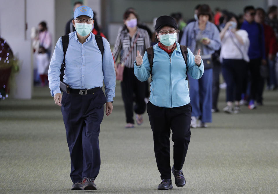 A passenger wearing a mask gestures as they arrive at Manila's international airport, Philippines, Thursday, Jan. 23, 2020. The government is closely monitoring arrival of passengers as a new coronavirus outbreak in Wuhan, China has infected hundreds and caused deaths in that area. (AP Photo/Aaron Favila)