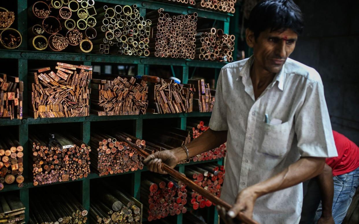 A worker handles a copper rod at a wholesale metal dealer in Mumbai, India