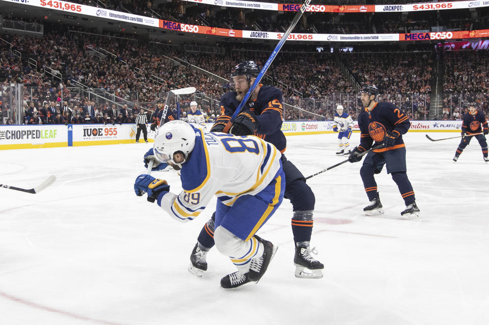 Buffalo Sabres' Alex Tuch (89) is checked by Edmonton Oilers' Mattias Ekholm (14) during first-period NHL hockey game action in Edmonton, Alberta, Thursday March 21, 2024. (Jason Franson/The Canadian Press via AP)