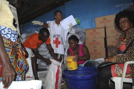 Red Cross workers distribute food at a World Food Programme storage center in Monrovia October 16, 2014. REUTERS/James Giahyue