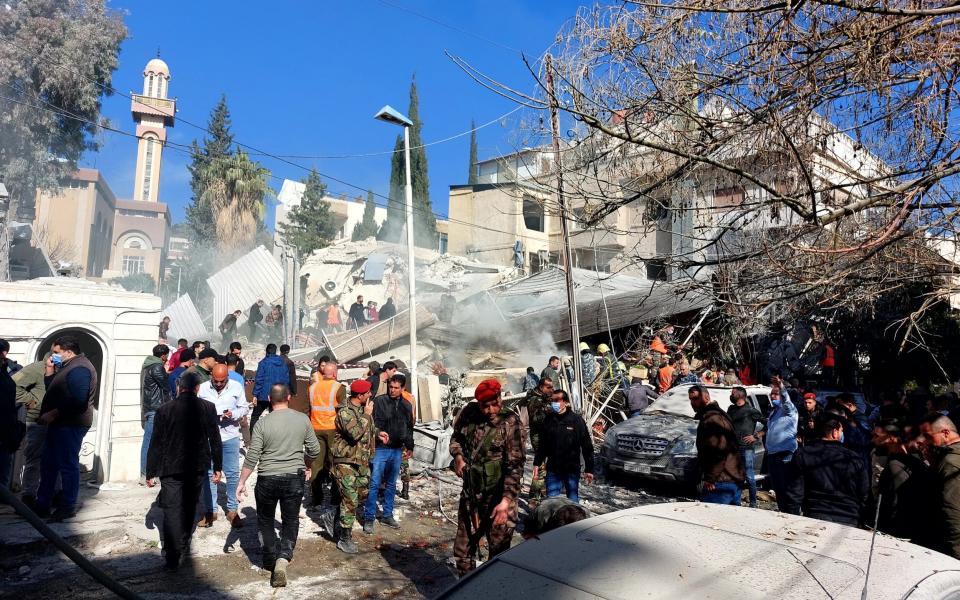 Civilians and security forces gather in front of a building destroyed in a reported Israeli strike in Damascus on January 20, 2024