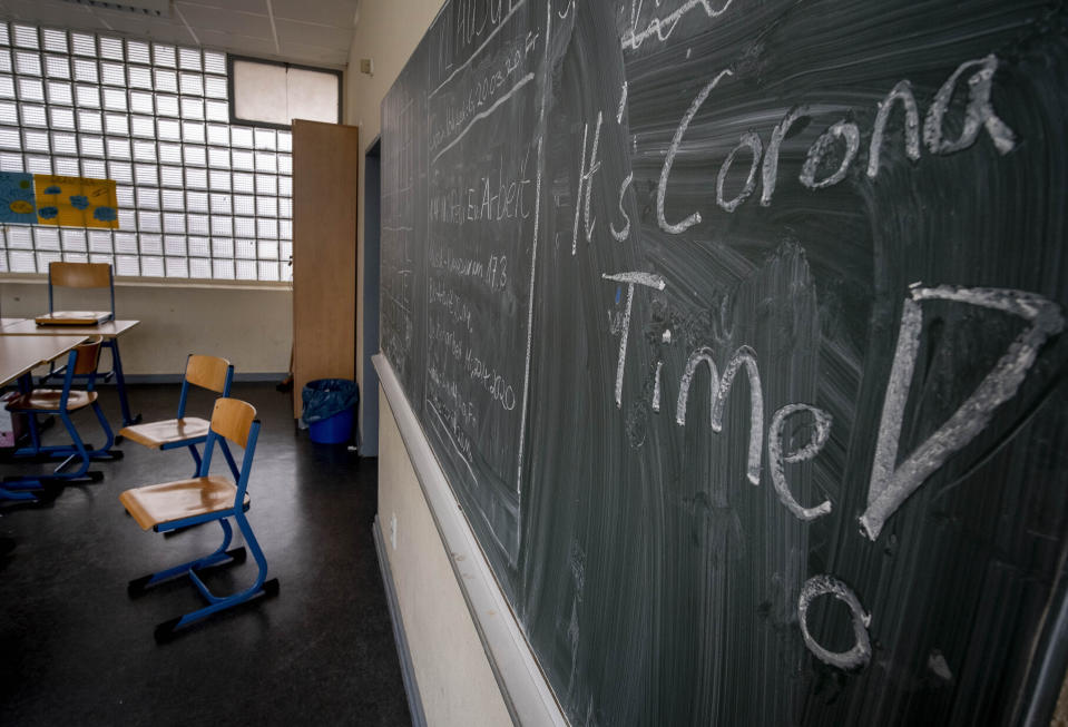 FILE - In this Friday, March 13, 2020 file photo the slogan 'It's Corona Time' is written on the chalkboard of an empty classroom of a high school in Frankfurt, Germany. The German government on Wednesday agreed on a strategy to boost the use of data for commercial purposes and signed a deal with state education authorities to fund laptops for teachers who have to work from home because of the virus lockdown. (AP Photo/Michael Probst, file)