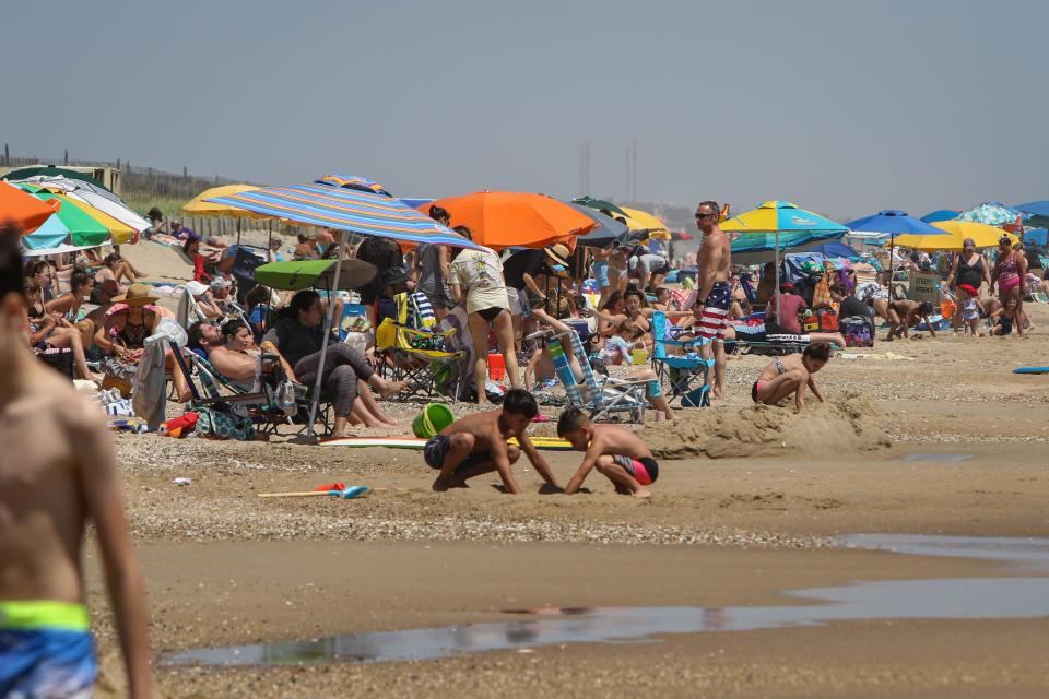A family wearing masks head down to a crowded Bethany Beach on a warm breezy Wednesday in 2020.