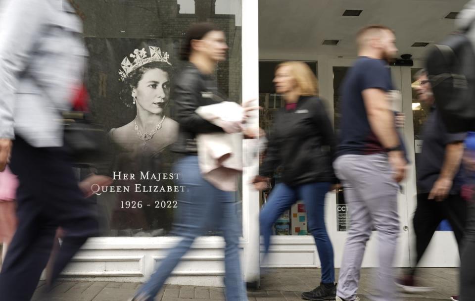 People walk past the window of a shop in Windsor paying tribute to the Queen (Andrew Matthews/PA) (PA Wire)