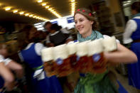 A waitress holds glasses of beer during the opening of the 186th 'Oktoberfest' beer festival in Munich, Germany, Saturday, Sept. 21, 2019. (AP Photo/Matthias Schrader)