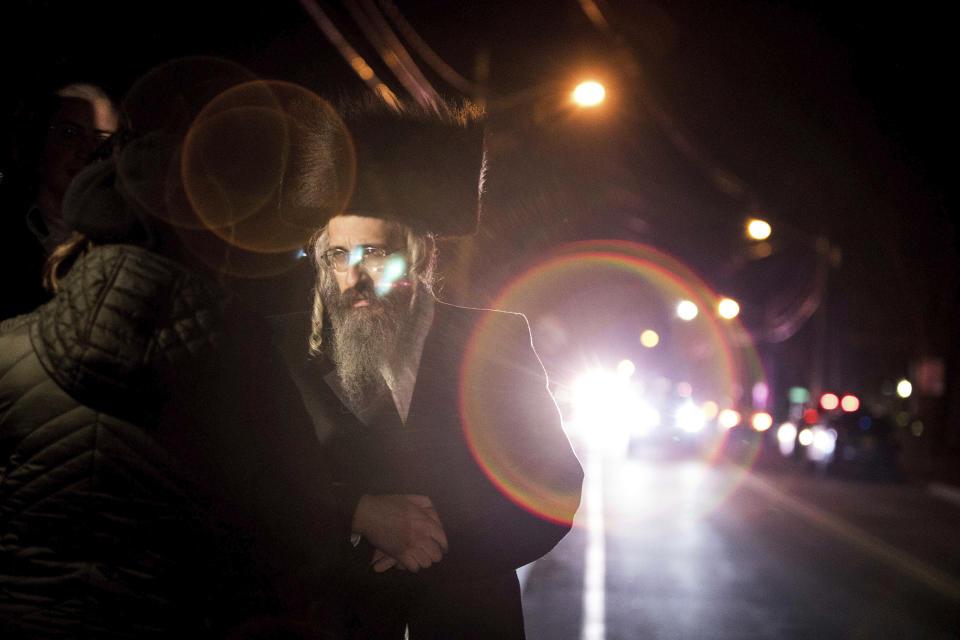 Orthodox Jewish people gather on a street in Monsey, N.Y., on early Sunday, Dec. 29, 2019, following a nearby stabbing late Saturday at a Hanukkah celebration. A knife-wielding man stormed into a rabbi's home and stabbed five people in the Orthodox Jewish community north of New York City. (AP Photo/Allyse Pulliam)
