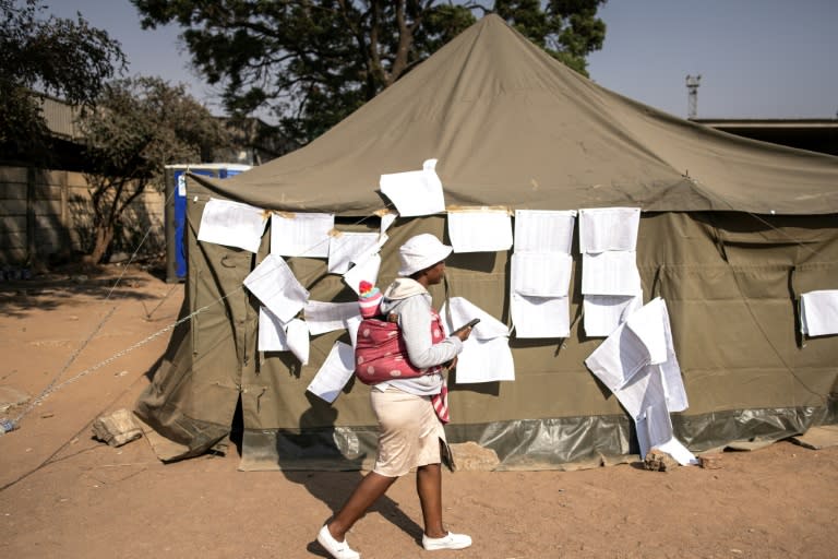 A woman walks past the electoral roll at a polling station in Harare in Zimbabwe's problem-marred vote (JOHN WESSELS)