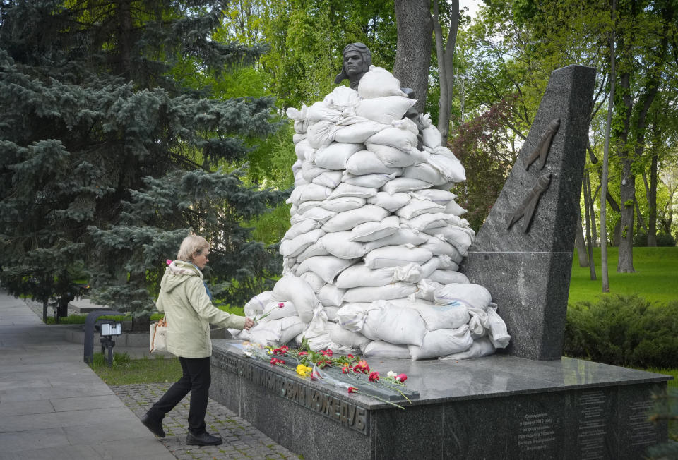 A woman lays flowers at the Unknown Soldier Tomb, protected by sandbags, on the occasion of the Victory Day in World War II, in Kyiv, Ukraine, Monday, May 9, 2022. (AP Photo/Efrem Lukatsky)