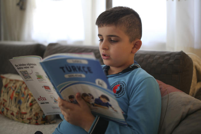 Amr Sayed Darwish, 10, a Syrian refugee reads a Turkish textbook at home in Istanbul, Friday, Sept. 17, 2021. Fatima Alzahra Shon thinks neighbors attacked her and her son Amr in their Istanbul apartment building because she is Syrian. The 32-year-old refugee from Aleppo was confronted on Sept. 1 by a Turkish woman who asked her what she was doing in "our" country. Shon replied, "Who are you to say that to me?" The situation quickly escalated. (AP Photo/Emrah Gurel)