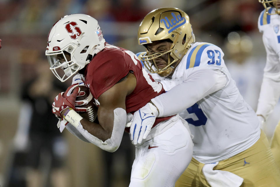 UCLA defensive lineman Jay Toia (93) brings down Stanford running back E.J. Smith (22) during an NCAA college football game, Saturday, Oct. 21, 2023, in Stanford, Calif. (AP Photo/Scot Tucker)