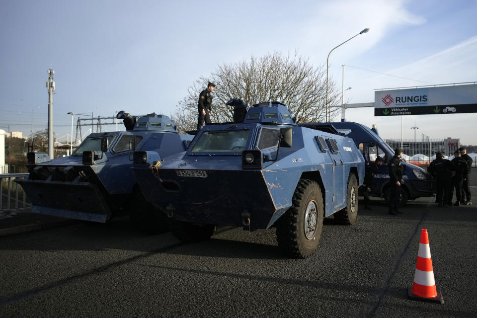 A gendarme stands atop a military vehicle at the entrance of the Rungis International Market, which supplies the capital and surrounding region with much of its fresh food, Monday, Jan. 29, 2024 south of Paris. Protesting farmers intended to encircle Paris with barricades of tractors, aiming to lay siege to France's seat of power in a battle with the government over the future of their industry shaken by the repercussions of the Ukraine war. (AP Photo/Christophe Ena)