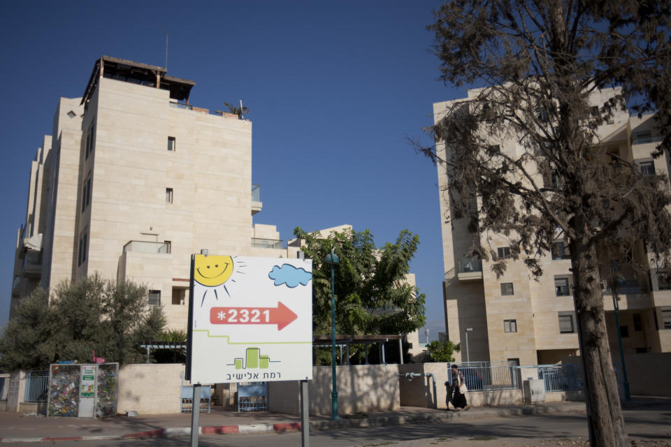 In this photo taken on Thursday, Sept. 20, 2012, an Israeli woman walks past a new housing project for religious Jews in Israel's mixed Arab-Jewish town of Lod, central Israel. Religious Jews who are the bedrock of the settlement movement have marked Israel's mixed Arab-Jewish cities as the new front to "reclaim," pushing into Arab neighborhoods to cement the Jewish presence there. The migration of several thousand devout Jews to rundown areas of Jaffa, Lod, Ramle and Acco has had a divisive effect far outweighing their absolute numbers, with Jews celebrating _ and Arab activists eyeing with mistrust and resentment _ the construction of Jewish seminaries and housing developments marketed exclusively to Jews. (AP Photo/Ariel Schalit)