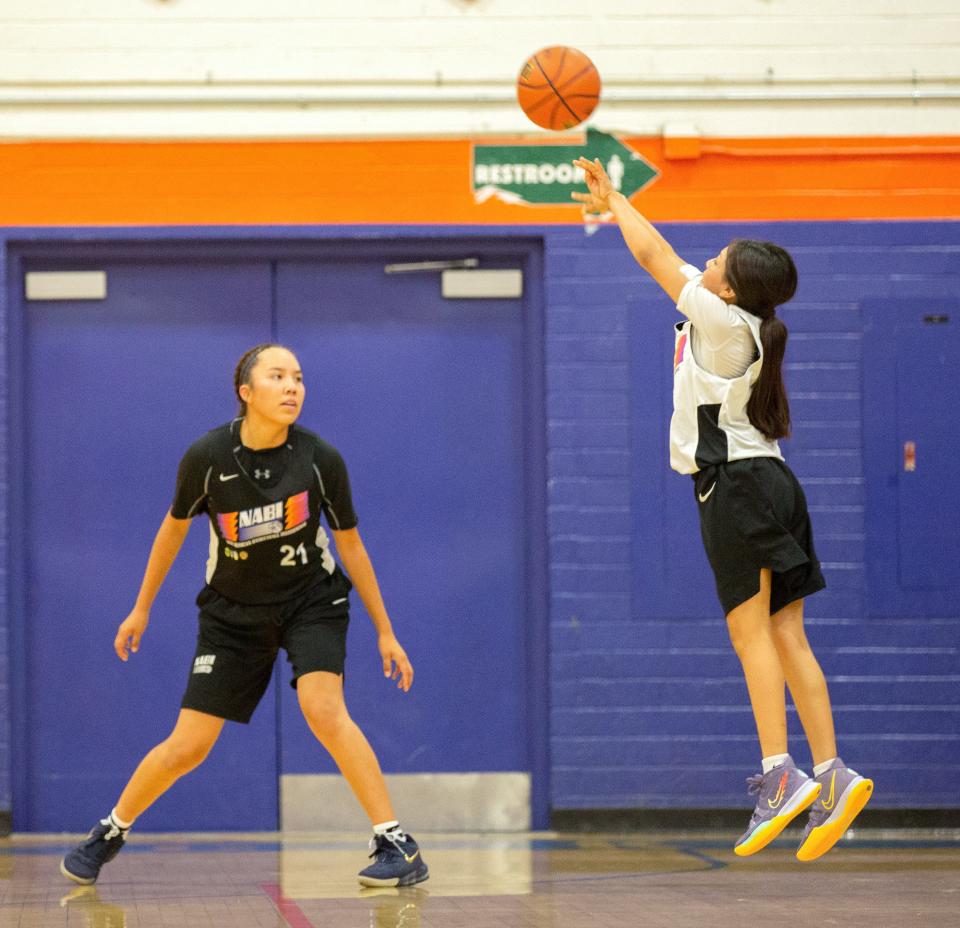 Kirtland Press guard Kaelynn Nez attempts a 3-point shot in front of New Mexico Elite guard/forward Lanae Billy during a Native American Basketball Invitational game at Camelback High School in Phoenix during the 2021 tournament.